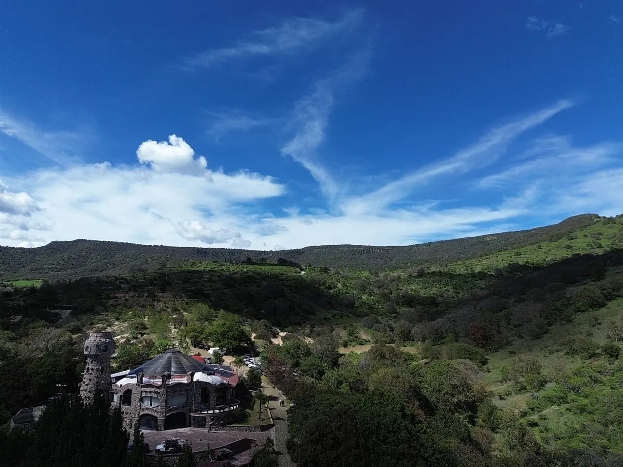 Toma aérea con dron de una construcción de piedra sobre la ladera, con la sierra al fondo